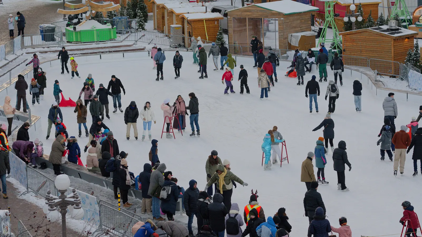 Patinoire extérieure à Québec remplie de patineurs en hiver, avec des chalets de bois à l'arrière-plan