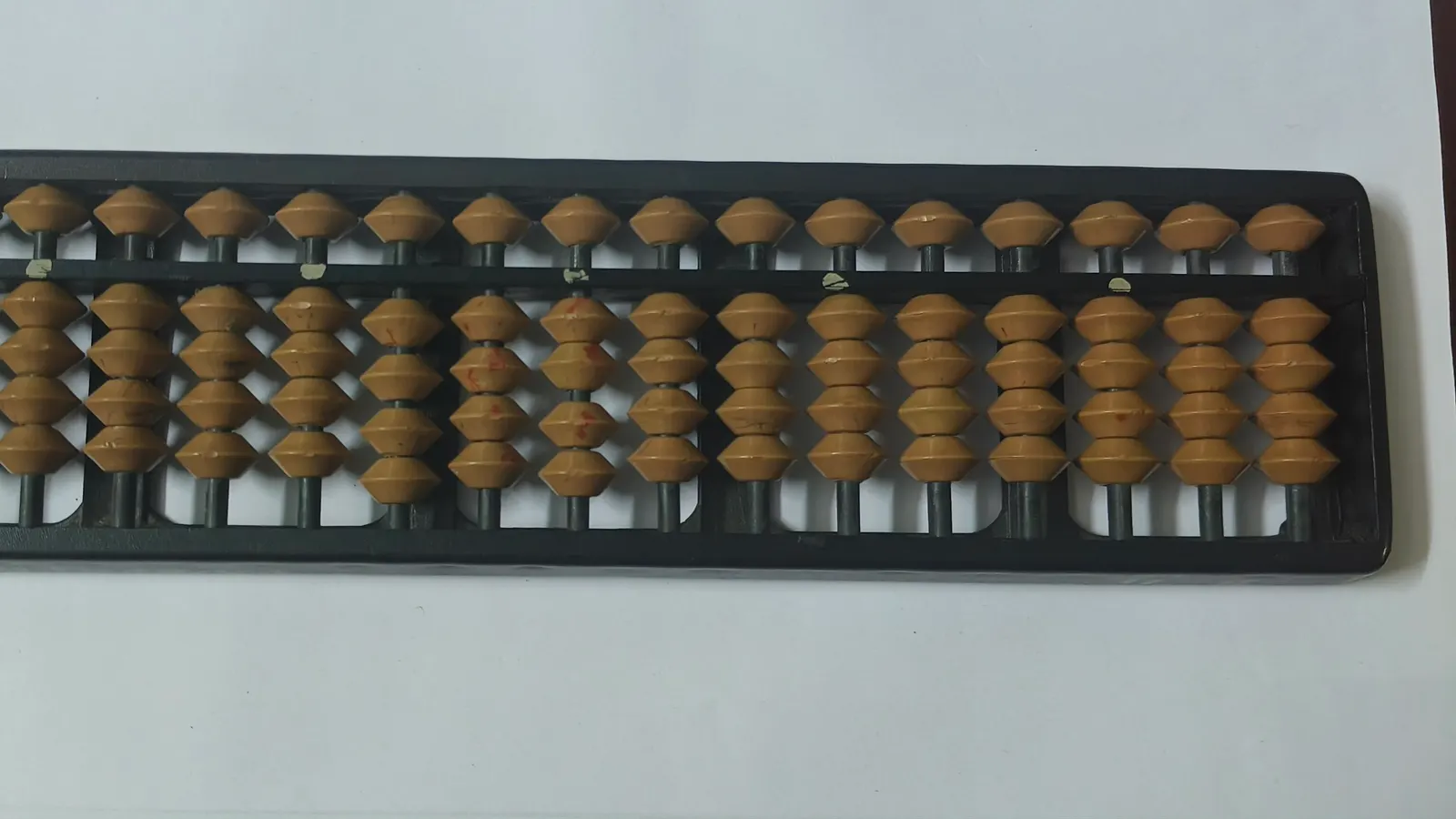 Boulier japonais à boules brunes sur un cadre noir, posé sur une table blanche