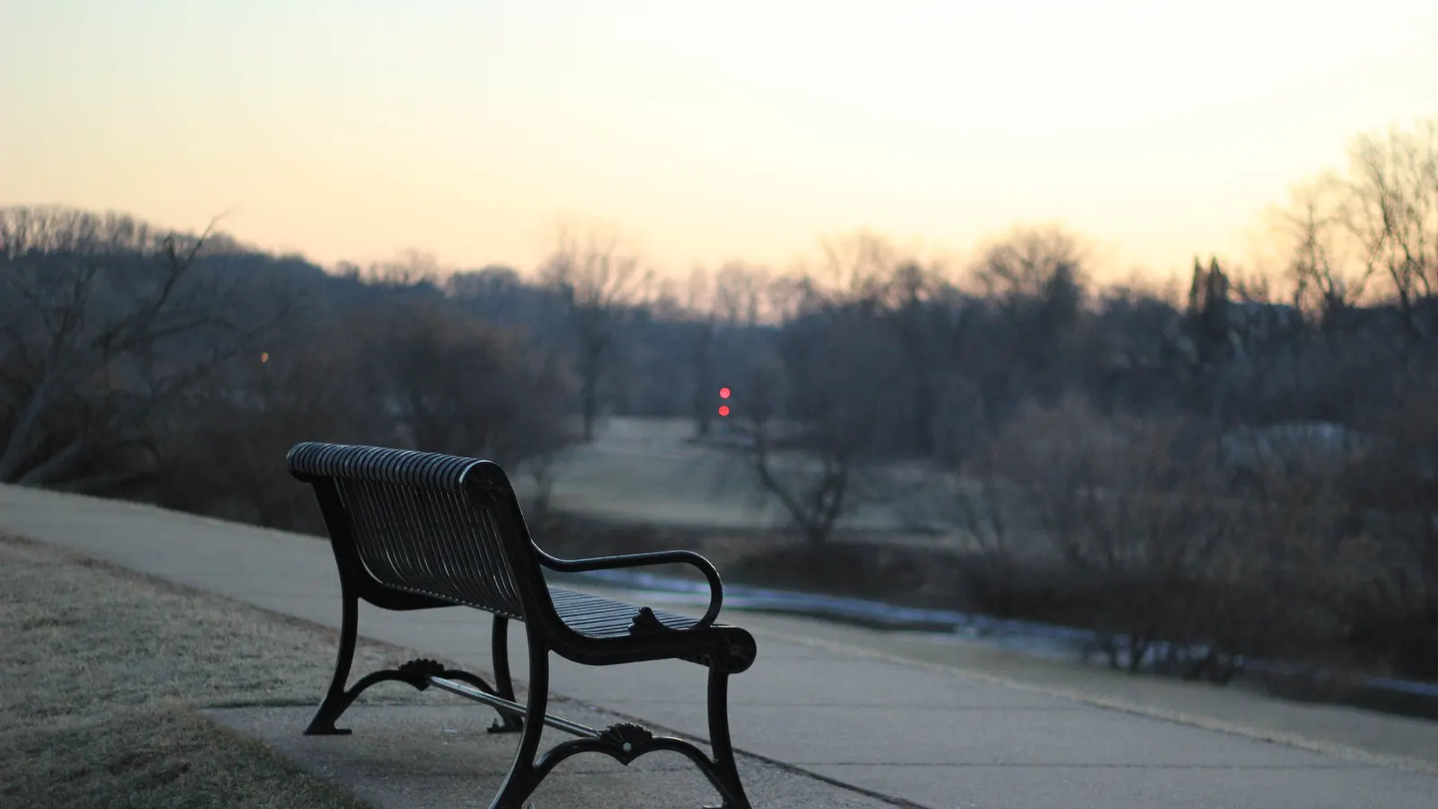 Banc de parc en métal noir tourné vers un paysage au lever du jour